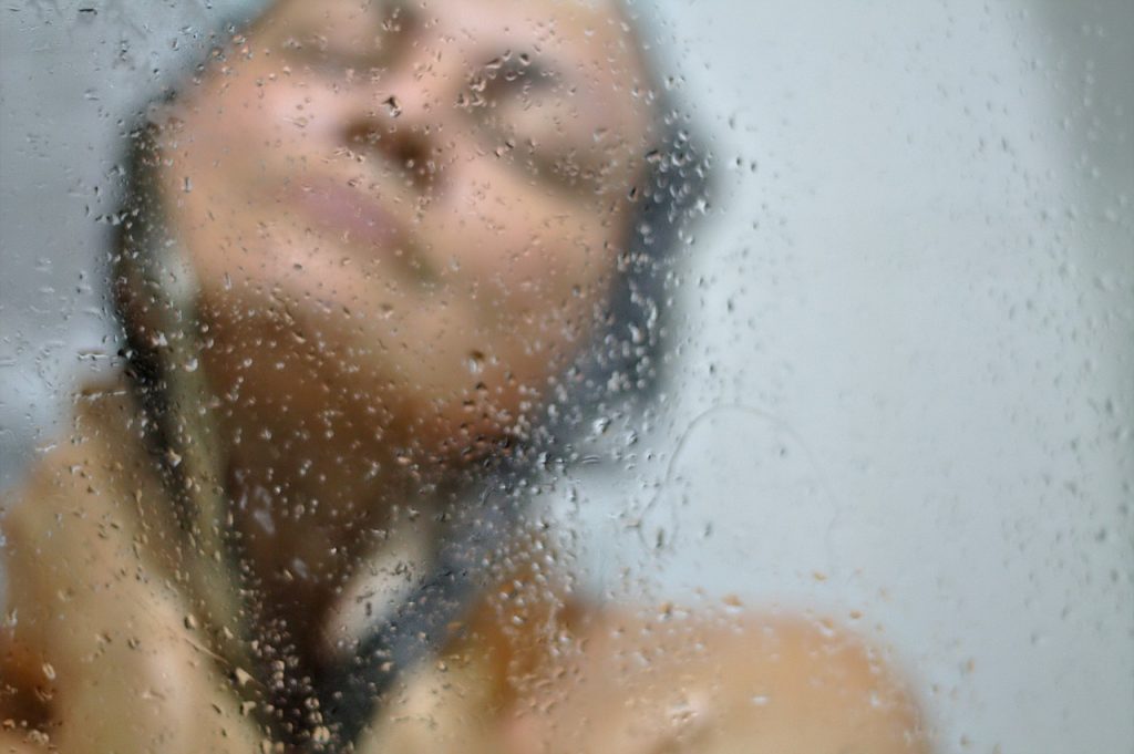 Woman Scrubbing Skin in Shower